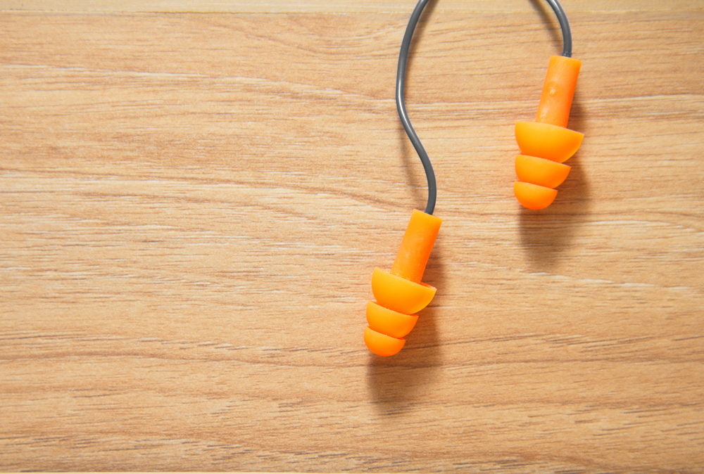 A pair of orange earplugs on a wooden table