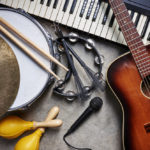 Musical instruments on a concrete floor: drums, guitar, keyboard, tambourine, and maracas