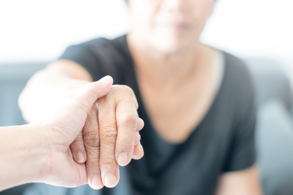 Elderly woman holding younger hand