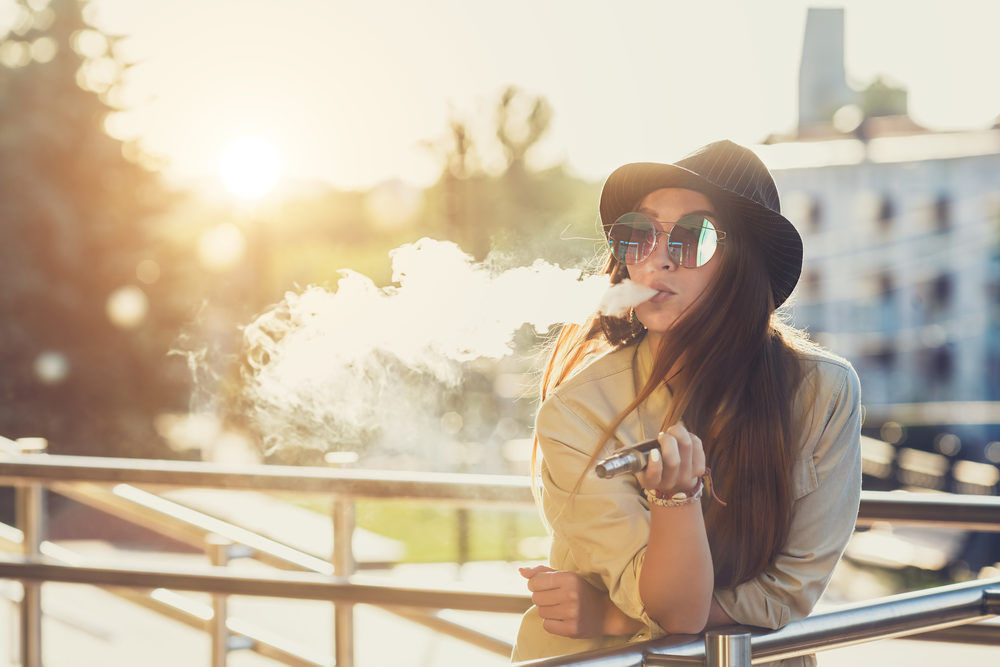 A young woman vaping outside