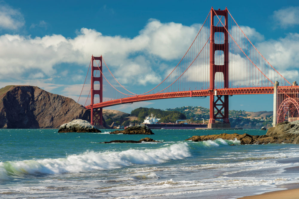 Waves crash on the shore in front of the Golden Gate Bridge