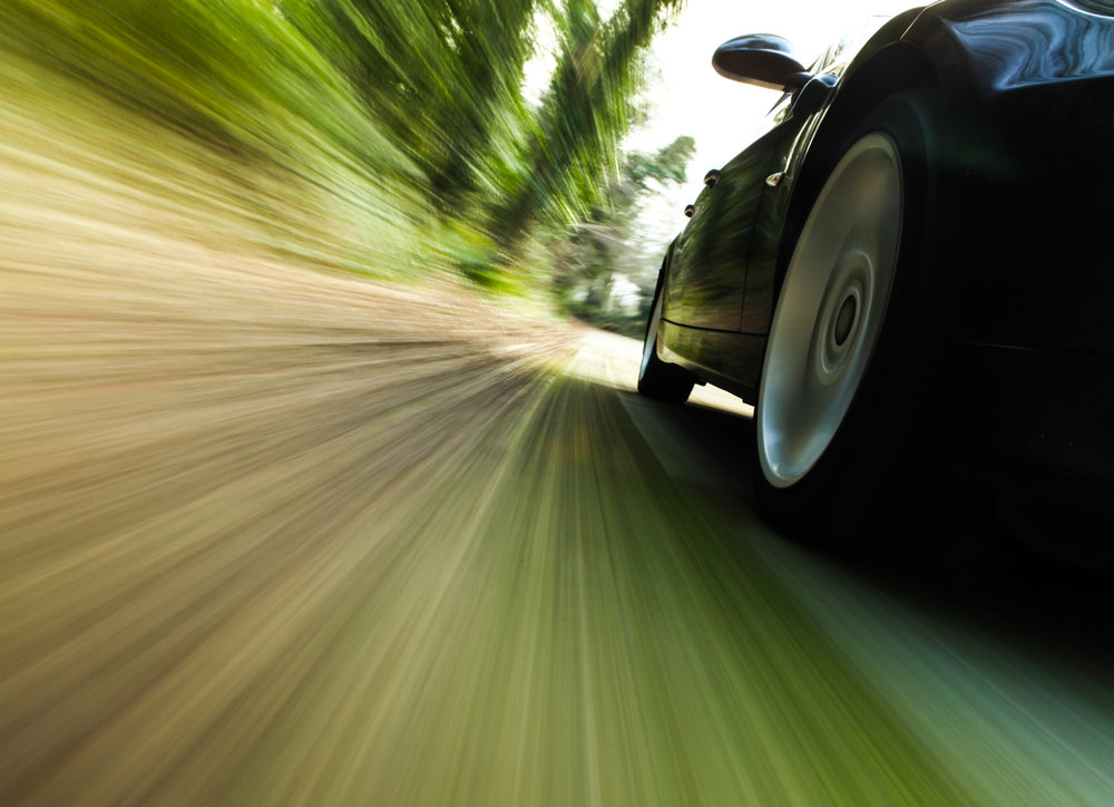 Front side view of black car driving fast.