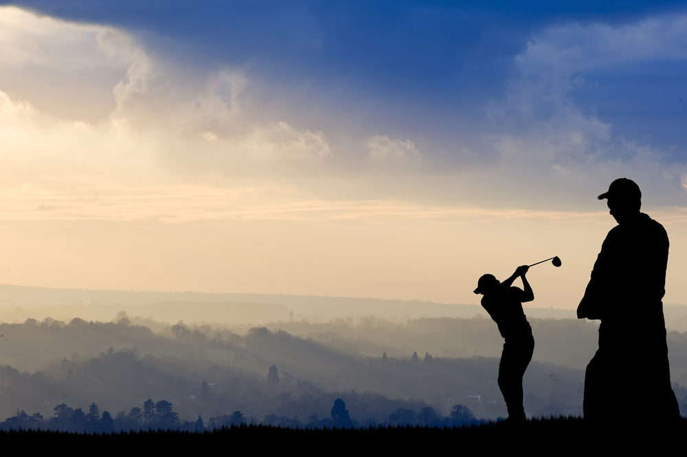 Silhouette of man playing golf on beautiful colorful sunset
