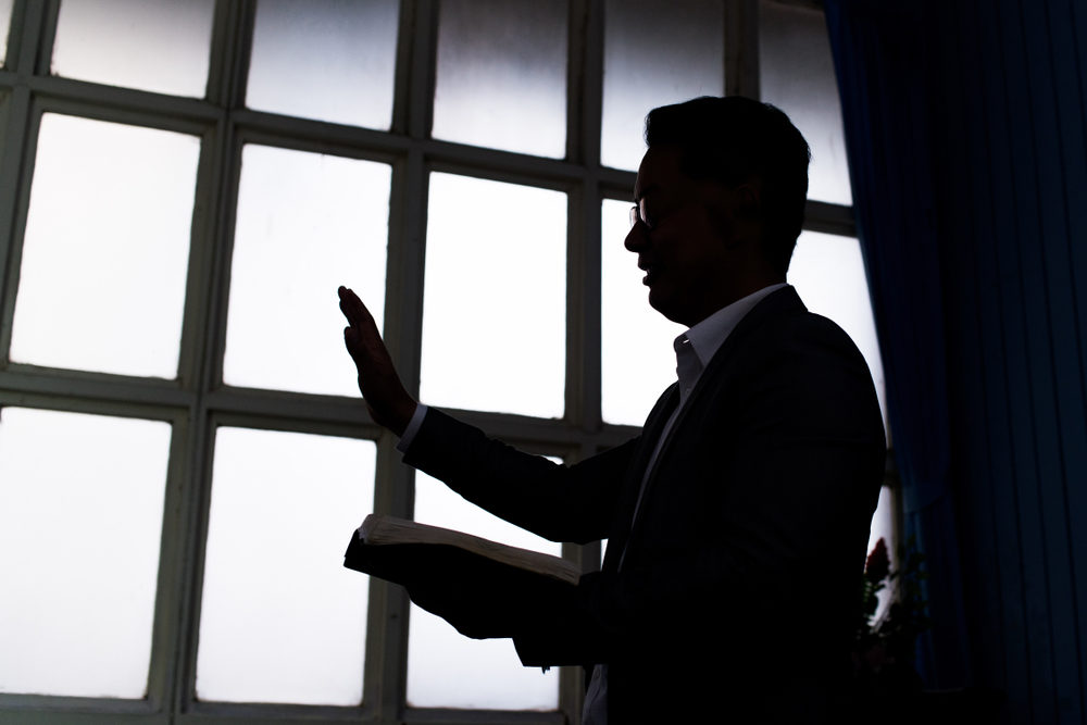 Silhouette of pastor wearing suit with rectangular window frame