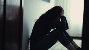 a distressed woman sitting on the floor holding her head 