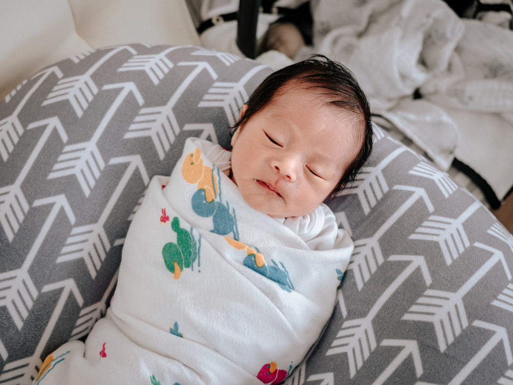 Asian baby boy sleeping on nursing lounger at home