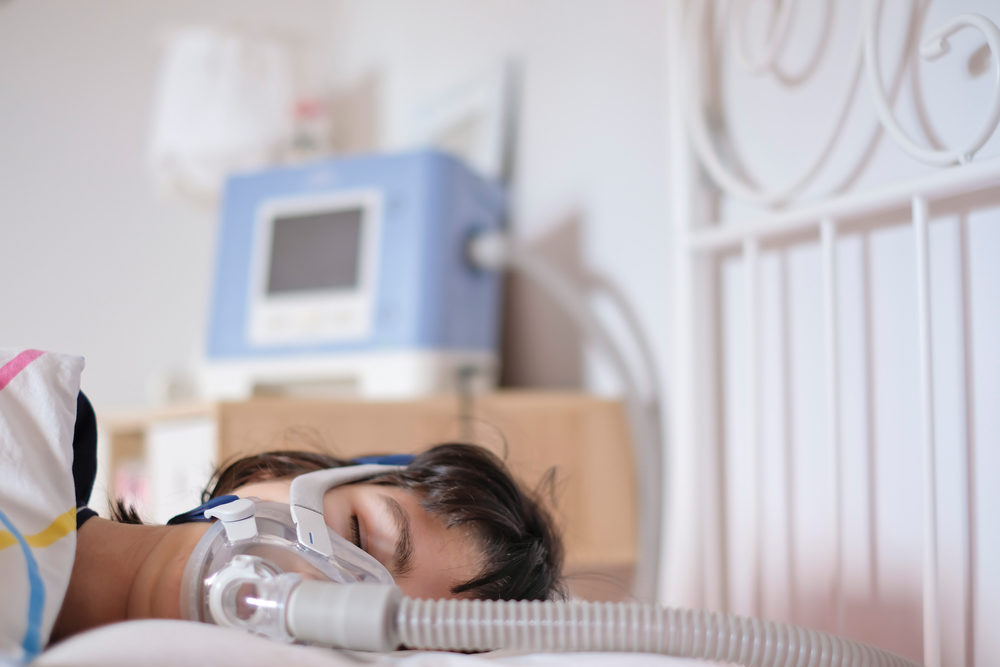 A woman sleeping in her bed with a ventilator