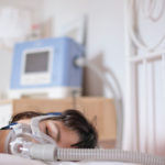 A woman sleeping in her bed with a ventilator