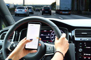 Woman sending message from a smartphone while driving a car
