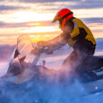 A man is riding snowmobile in mountains. 
