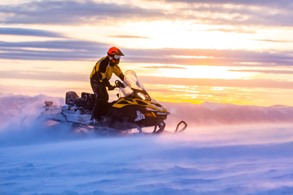 A man is riding snowmobile in mountains