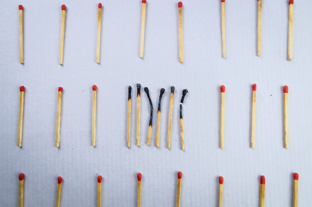 Burnt matches clustered in the center of several unburnt spread-out matches