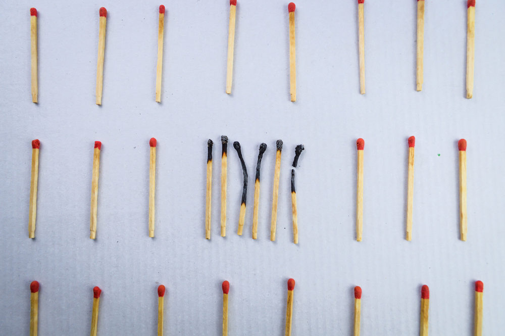 Corona Virus Update Burnt matches clustered in the center of several unburnt spread-out matches