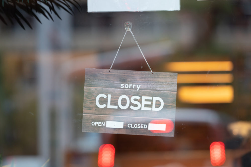 A sign reading "sorry CLOSED" hangs on a glass door