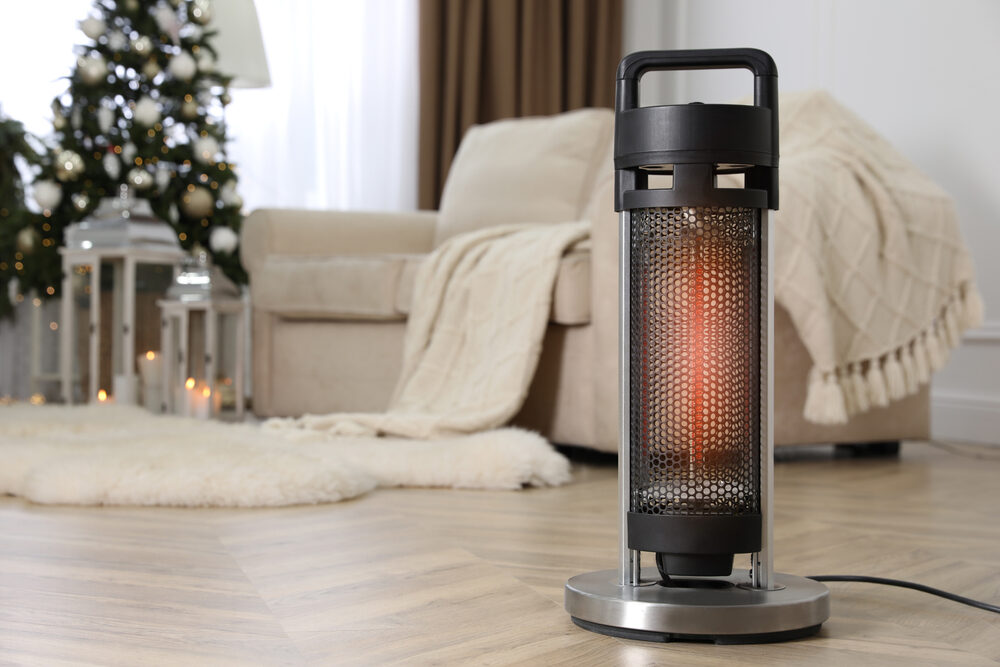 How Do Burn Injuries Occur During the Winter Months? a modern space heater on the floor in living room with couches and christmas tree in the background