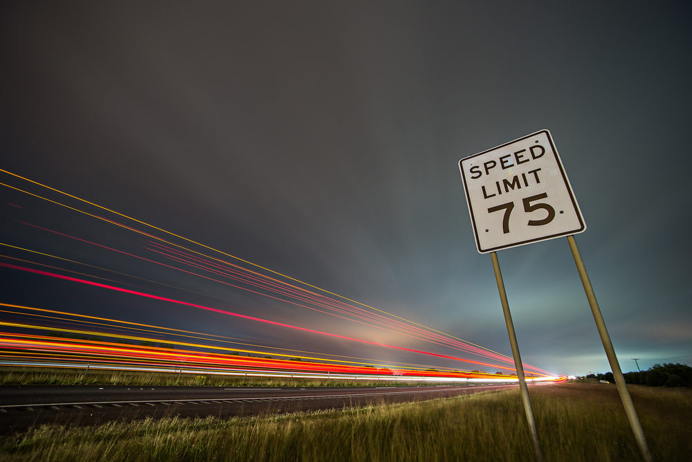 75mph speed limit sign at night next to a freeway 