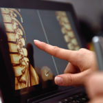 Hand pointing on screen with X-rays of the spine.