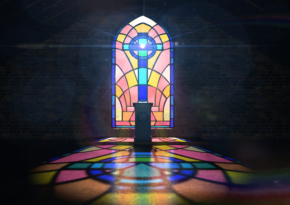  colorful stained glass window in the pattern of a crucifix reflecting colors on the floor and a speech pulpit