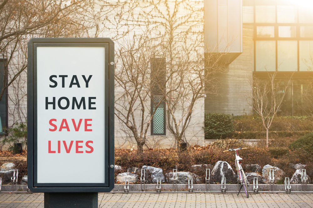 "STAY HOME SAVE LIVES" on an outdoor sign outside an office building