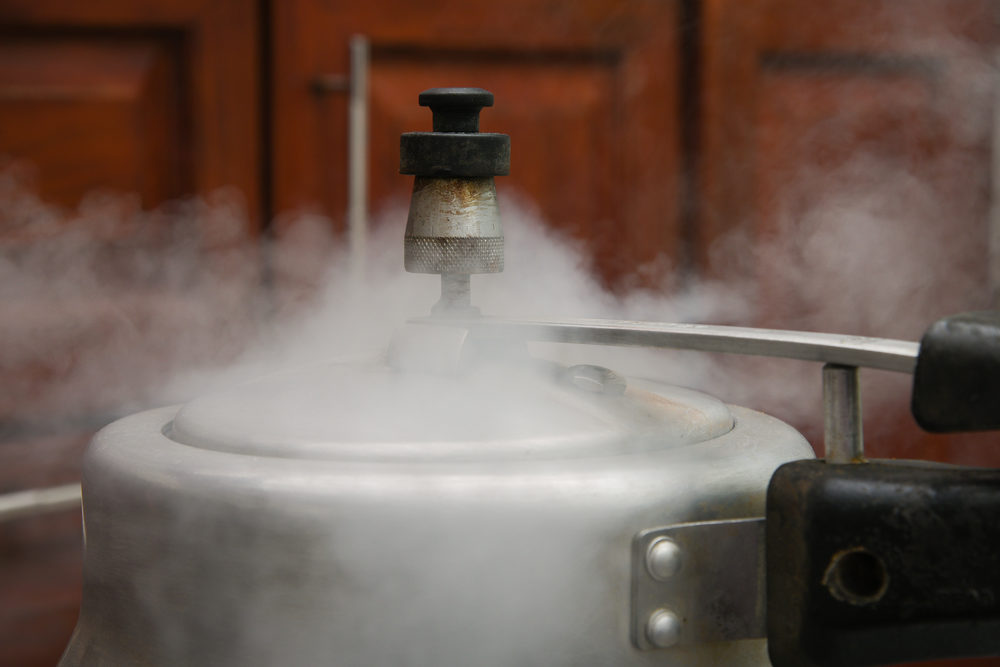 Illinois Woman Burned by Instant Pot Pressure Cooker Steam escaping from lid of pressure cooker with reflection of modern kitchen.