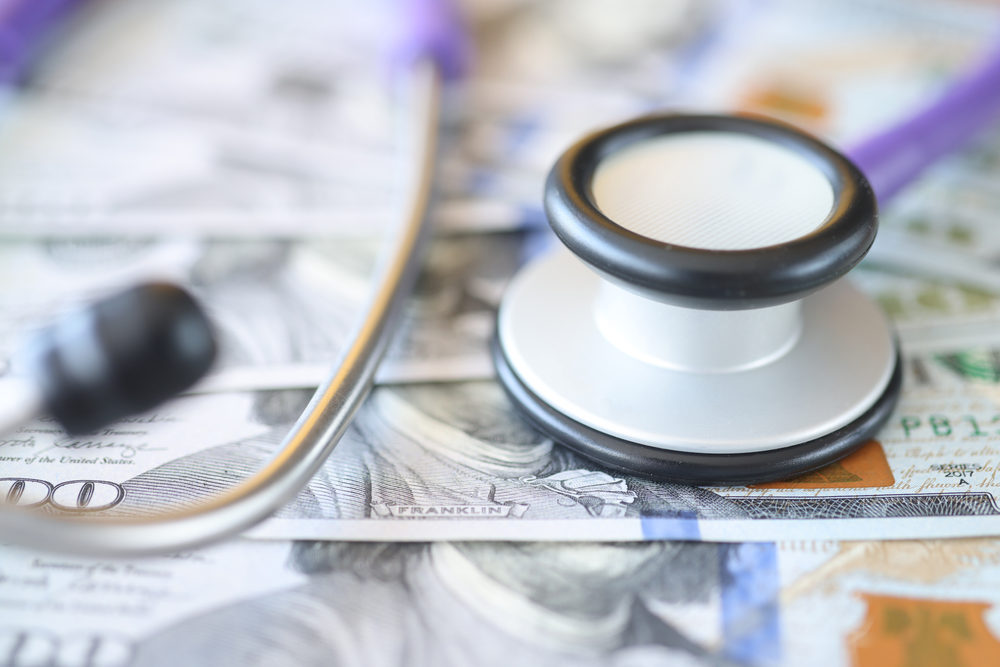 Medicare Fraud Is Happening Far Too Often stethoscope laying on a pile of one hundred dollar u.s. bills