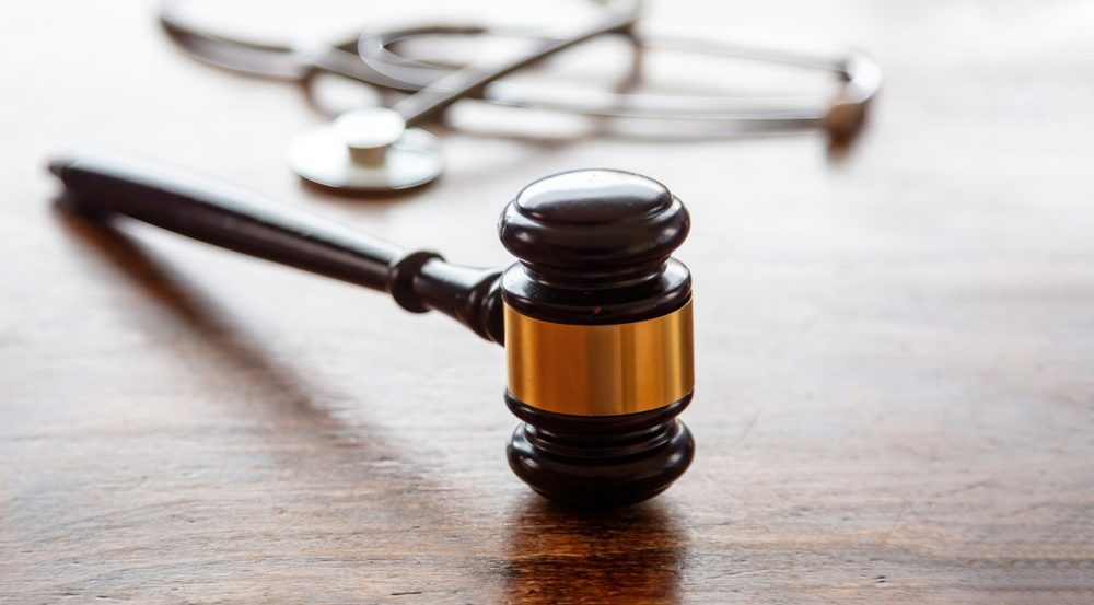  Judge gavel and doctor stethoscope on lawyer office desk.