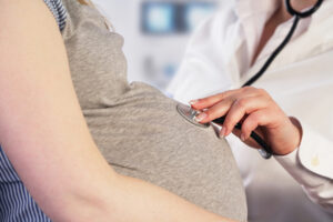 doctor listening to a pregnant woman's stomach with a stethoscope