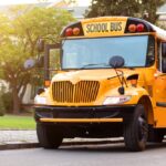 stopped yellow school bus outside of school building