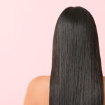 back view of long straight brunette hair on a female with a pink background