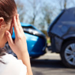 Stressed Female Driver Sitting At Roadside After Traffic Accident holding her head