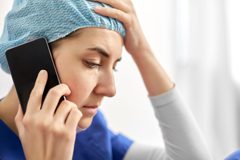 closeup of a stressed and sad nurse on the phone