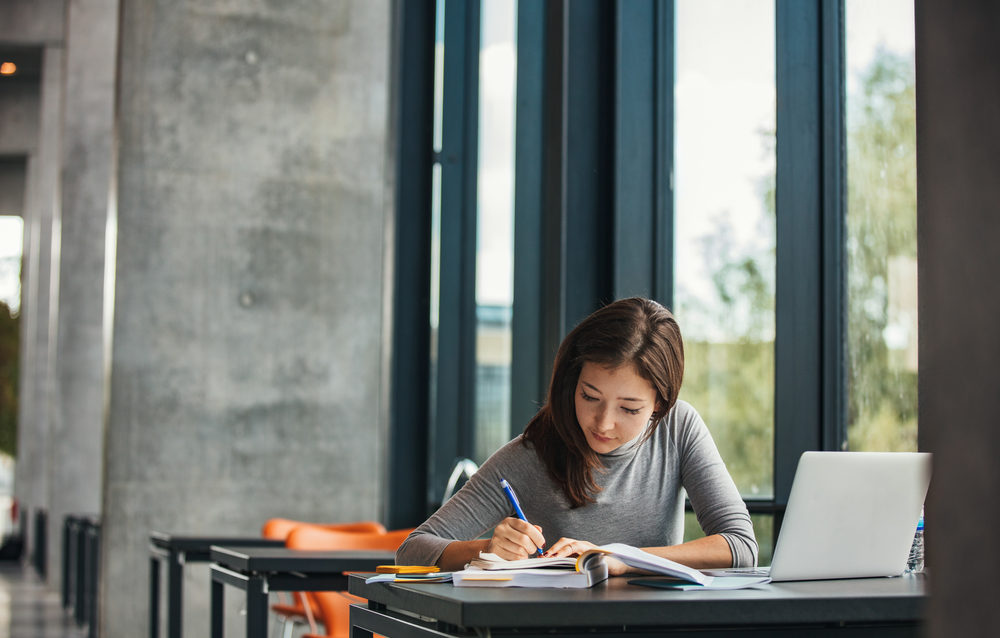 Settlement Planning for Sexual Assault Litigation A young woman at a desk in the library, taking notes and reading