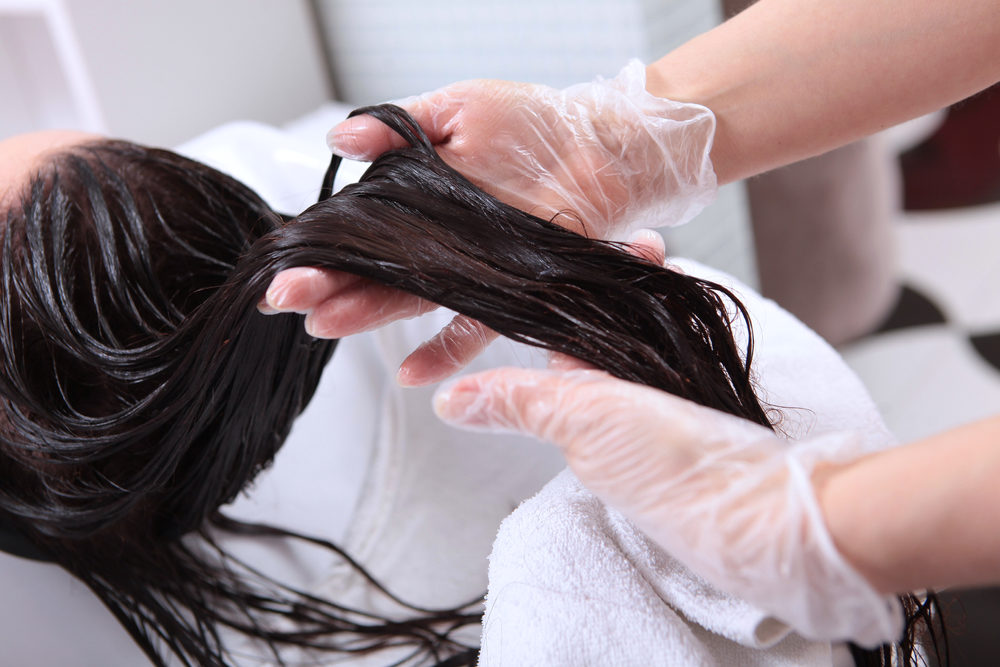 stylist applying chemicals to hair at a salon