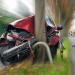 closeup of car crashed into a tree with blurred background