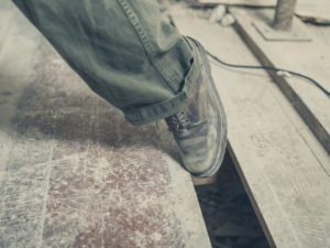 A shod foot caught in a gap between floorboards