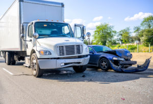 Collision of a semi truck with box trailer and a passenger car on the highway road