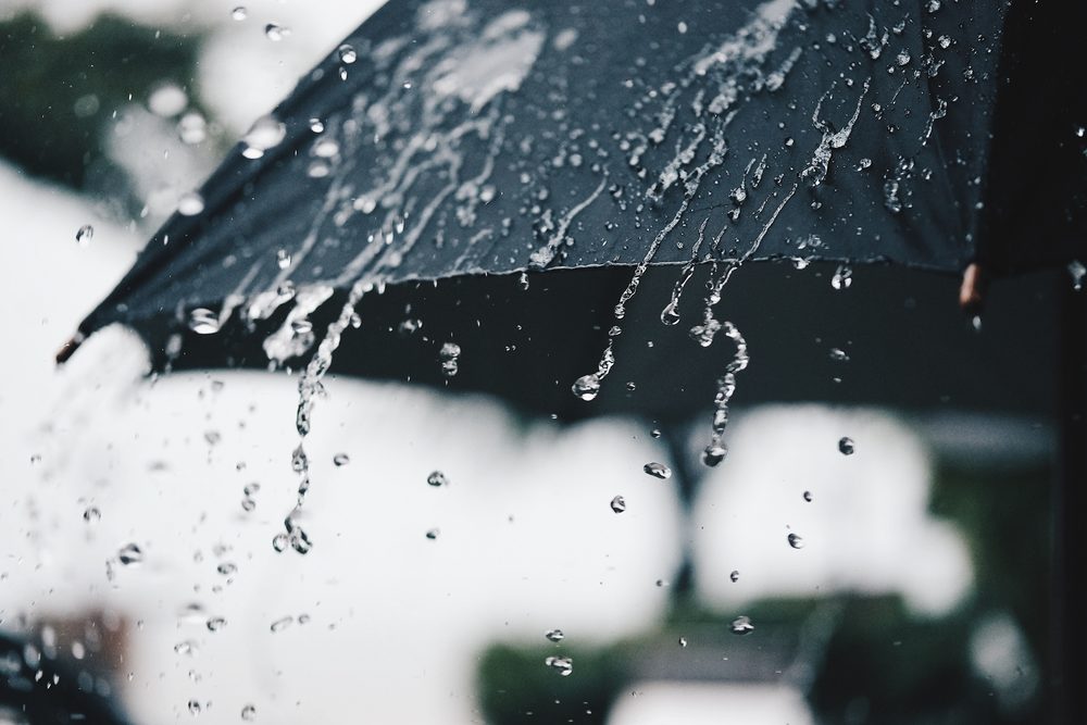 black umbrella with rain water falling off of it closeup