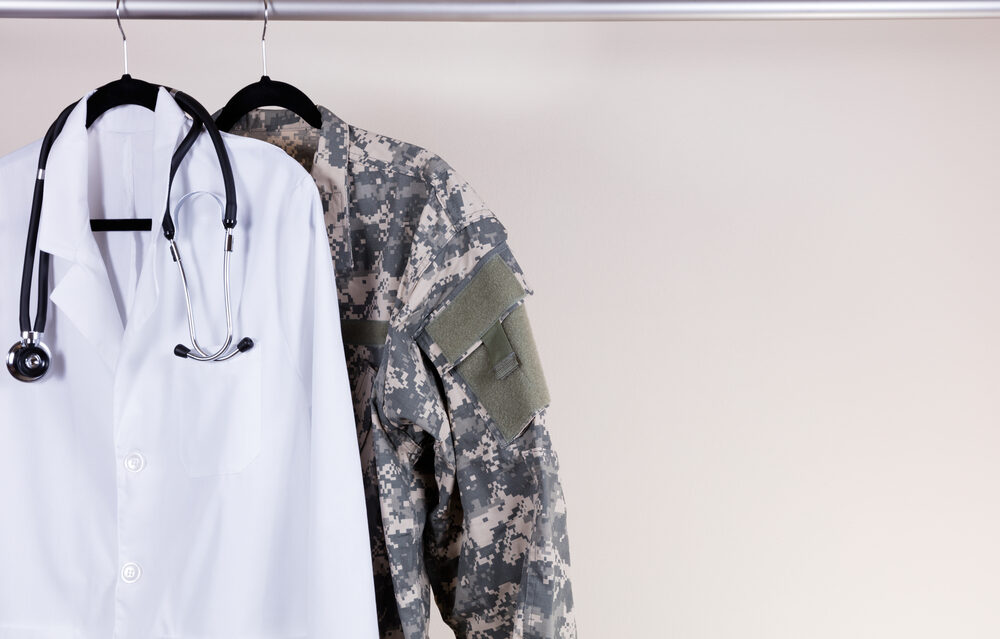 Medical Doctor Consultation white coat, stethoscope around collar, and military uniform hanging on rack.