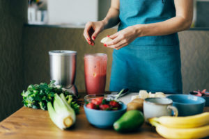 A woman puts the ingredients in a blender bowl to make a spring fruit and berry smoothie.