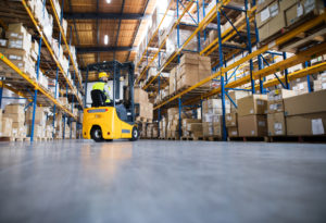 A forklift moving amongst shelves full of boxes in a warehouse
