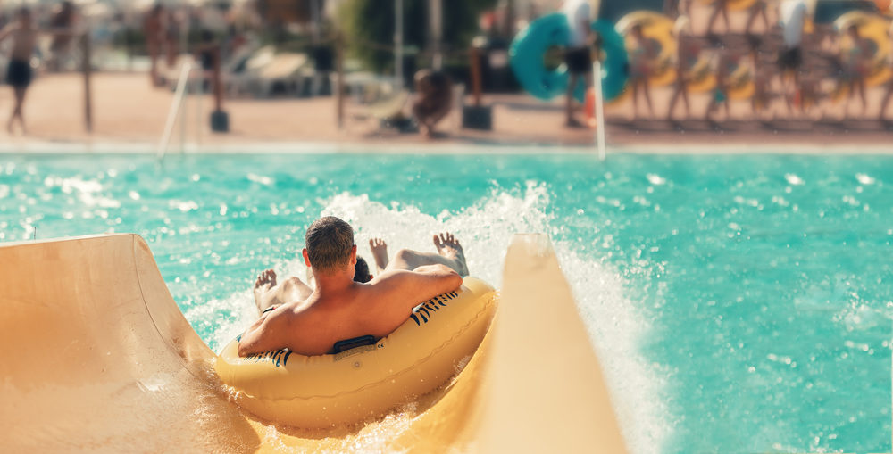 A man and child on a raft splash into the pool at the end of a waterslide