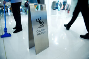 caution wet floor sign in mall while worker cleaning