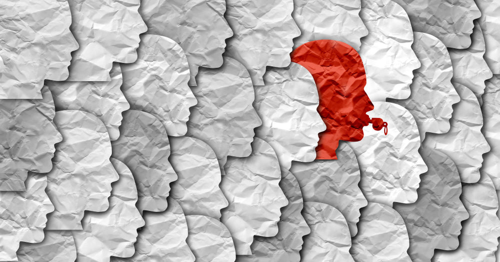 What Is A Whistleblower? whistleblower concept with grey and white head shapes with a red one with a whistle