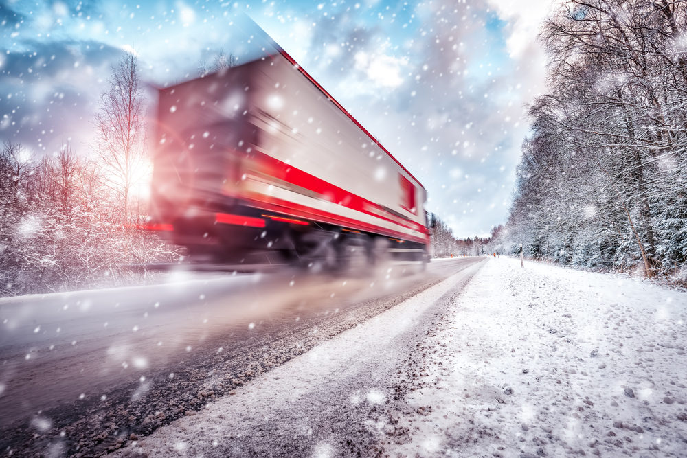 Tips For Safe Holiday Travel Around Large Trucks Truck on asphalt road in winter on sunny morning