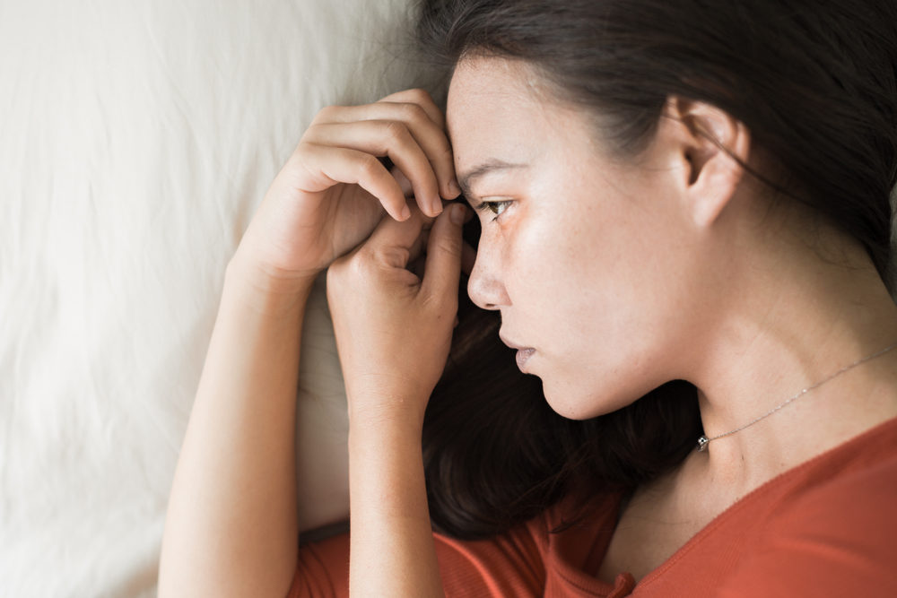 Sad woman lying in bed, depressed.