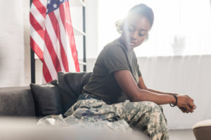 Female army soldier in camouflage clothes sitting on sofa