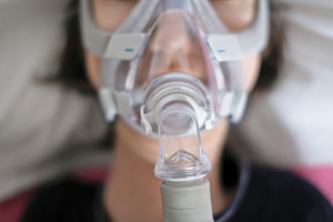 A woman sleeping in her bed with a ventilator