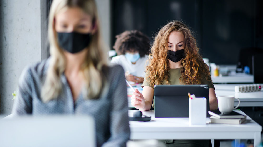 Women in the Workplace: Equal Pay Day 2022 Young people with face masks back at work or school in office after lockdown.