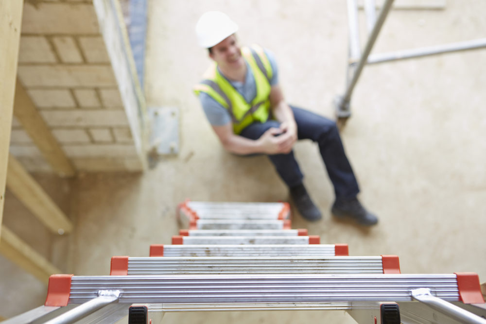 Male construction worker holding knee after falling off a ladder at a jobsite