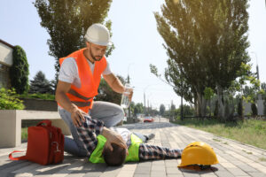 Worker with bottle of water helping colleague on city street who is suffering from heat stroke